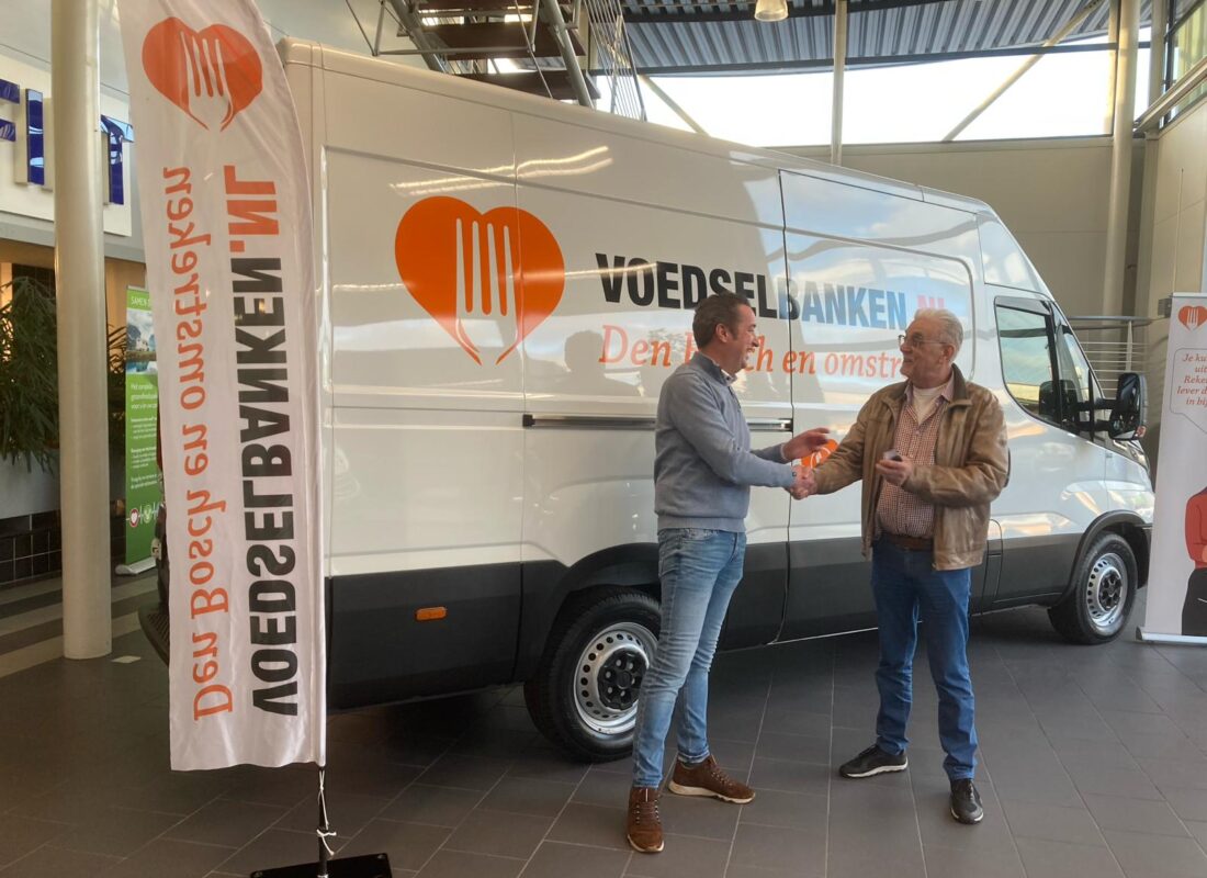 Sleutel van de nieuwe bus wordt overhandigd. Op de witte bus staat groot het logo van de Voedselbank.